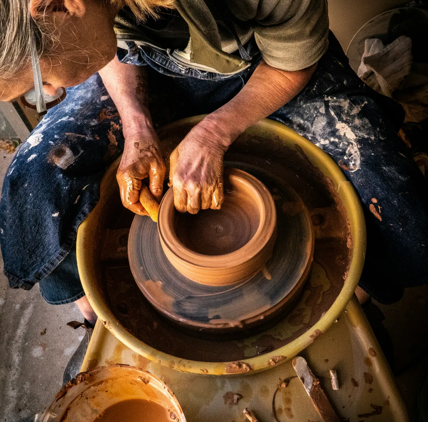 A potter’s hands shaping clay on a spinning wheel
